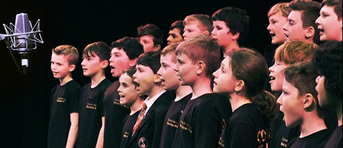 Children's choir on stage next to a microphone