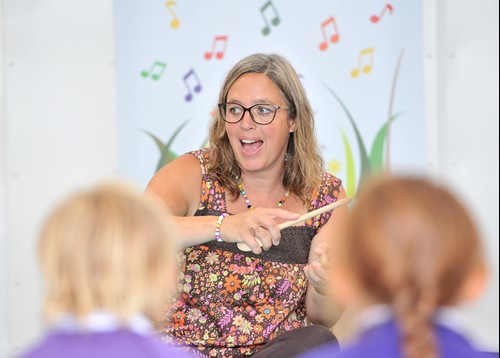 teacher leading musical activity in front of children